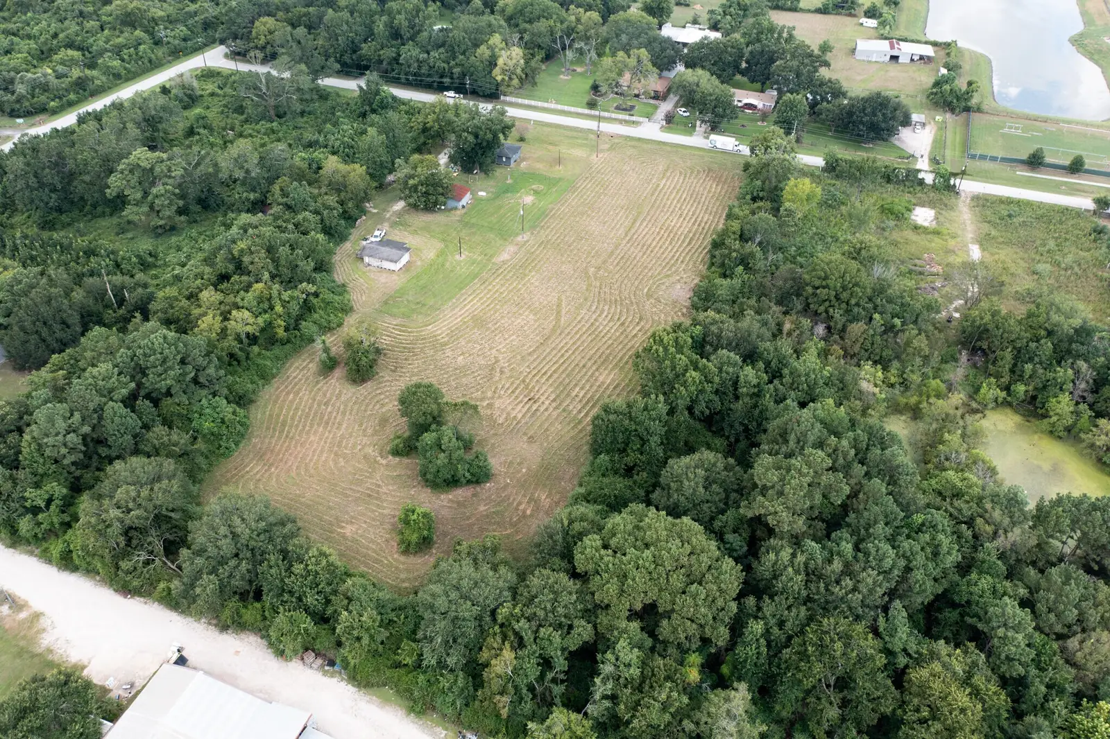 Aerial of the site showing the cleared pasture, mature trees and a pond on adjacent land