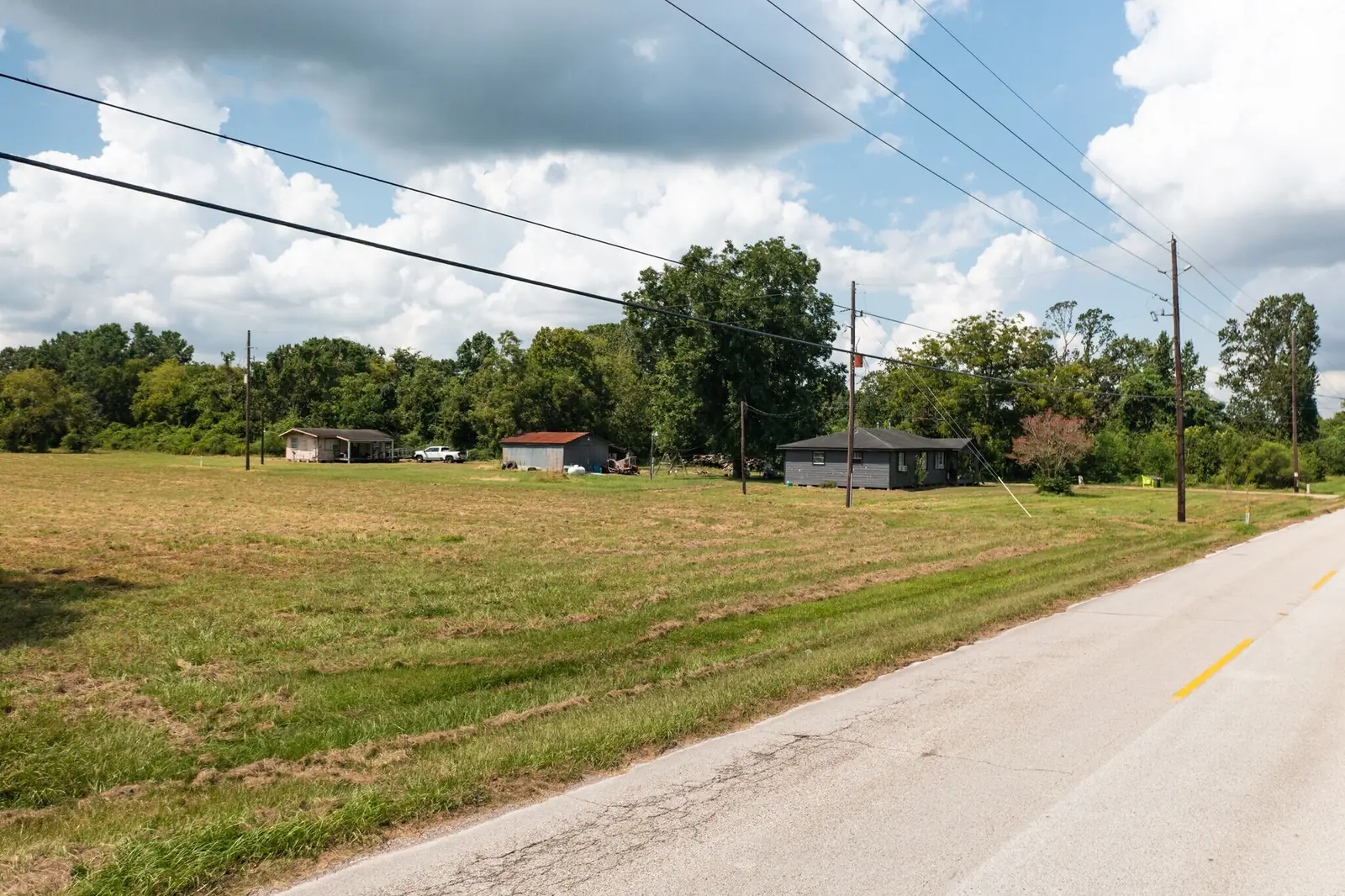 View across the open pasture from Medical Complex Drive toward the existing house and outbuildings